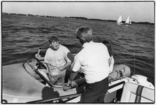 841707 Afbeelding van toezichthouder en een jongen in een motorbootje in een meer of een plas in de provincie Utrecht.